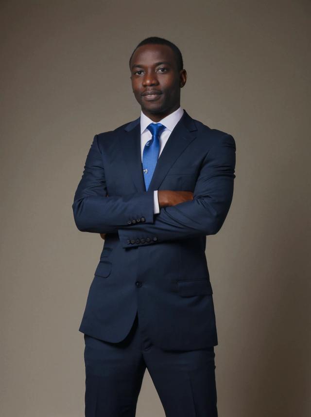 professional business photo of an african man with his arms crossed standing confidently against a dark gray background. He is wearing a nice dark blue business suit and a vivid blue tie